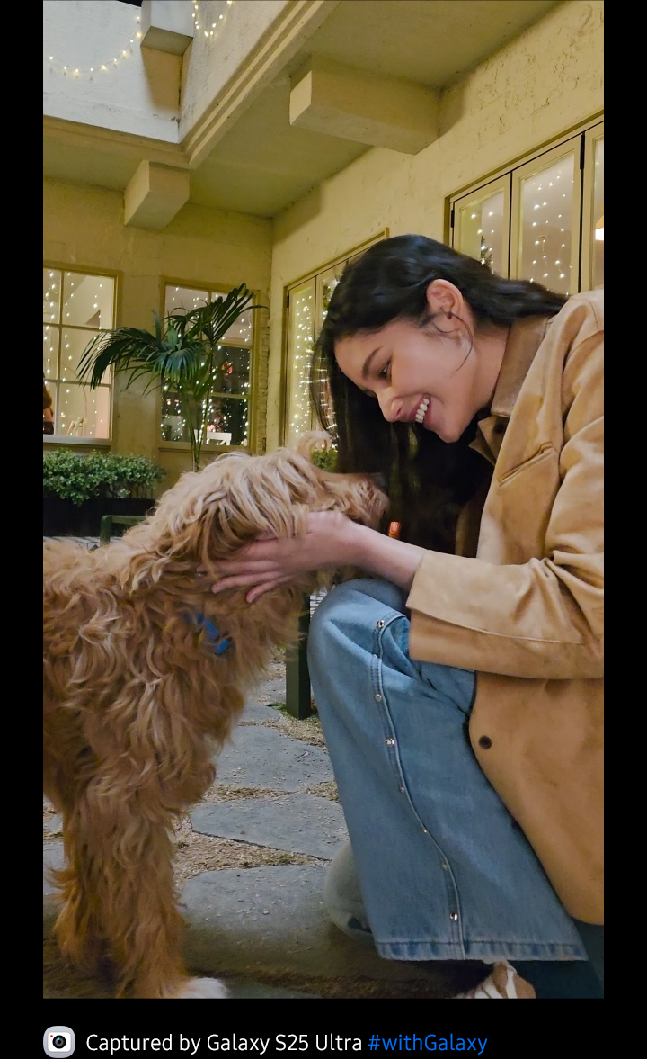 Footage is shot of a woman and her dog outside in the evening. The dog runs towards the woman and the footage is clear thanks to Galaxy S25 Ultra's camera.