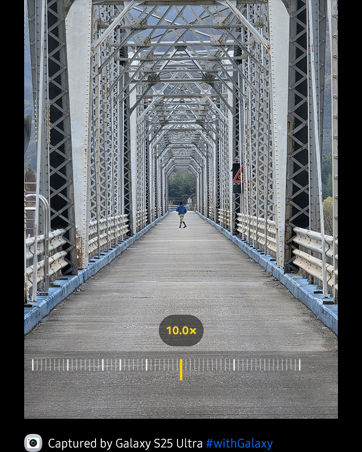 Subject is seen crossing a bridge at 0.6 times zoom. Then, 1 times zoom, 2 times zoom, 3 times zoom, 5 times zoom, 10 times zoom, 30 times zoom, 50 times zoom, 70 times zoom, 100 times zoom and then back down to 10 times zoom. Whether zoomed in or out, the details remain clear.