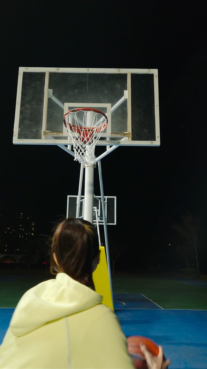 Two subjects play basketball in the evening. The footage is clear thanks to Galaxy S25 plus's camera.