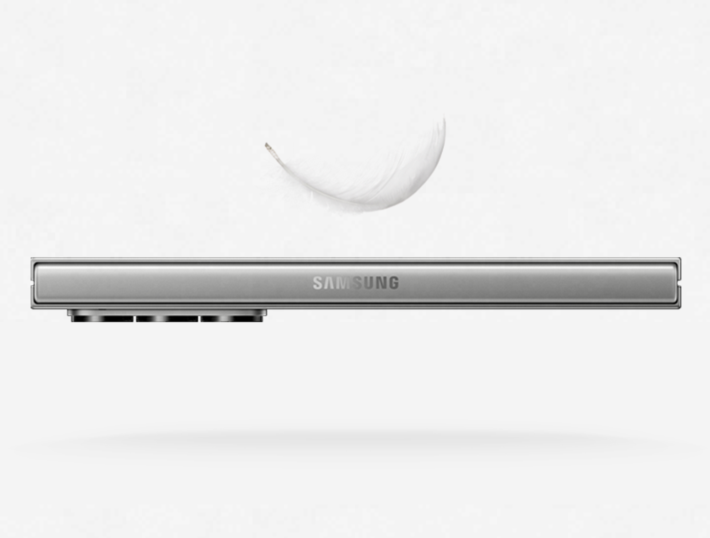 A Galaxy Z Fold6 in Silver Shadow becomes slimmer. Slanted, it unfolds. The surface of its rear camera lenses are shown.